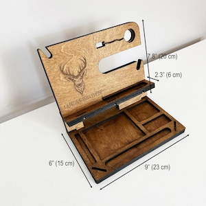 May include: Wooden organizer with a deer design and the name "LUCAS BROWN" engraved. It has compartments for a phone, watch, keys, and other accessories. The organizer measures 7.8 inches tall, 6 inches wide, and 9 inches long.