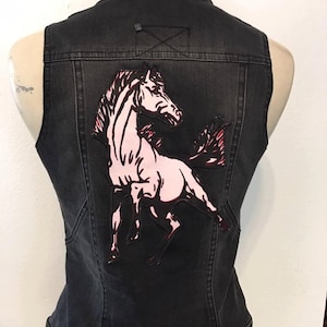 May include: Black denim vest with a pink and black horse applique on the back.