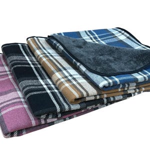 May include: Four plaid blankets stacked on top of each other. The top blanket is blue and white, the next is brown and white, the next is black and white, and the bottom blanket is pink and white.