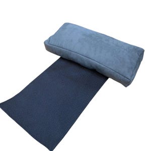 May include: A blue suede yoga bolster on top of a black yoga mat with white polka dots.