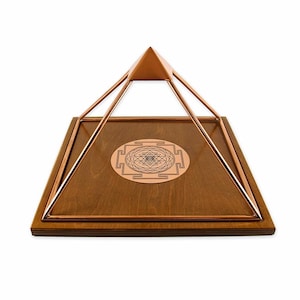 May include: A copper wire pyramid with a wooden base and a copper Sri Yantra symbol in the center. The pyramid is approximately 6 inches tall.