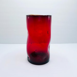 Może przedstawiać: Czerwony szklany wazon o falistym, fakturowanym wzorze.