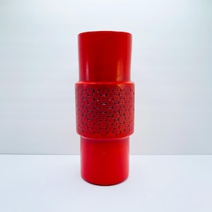 May include: A red ceramic vase with a geometric pattern around the middle.