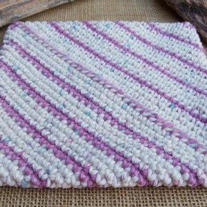 May include: A crocheted kitchen dishcloth with a diagonal pattern in white and pink yarn.