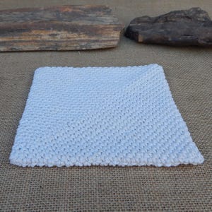 May include: A square, light blue, hand-knitted washcloth. The washcloth is made of a soft, textured yarn and has a simple, yet elegant design. The edges are neatly finished, and the overall appearance is clean and inviting.