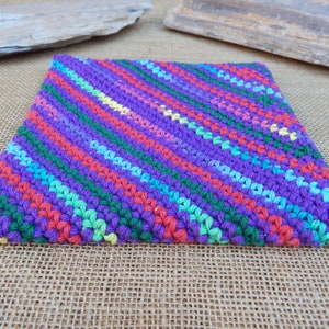May include: A colorful crocheted pot holder with a diagonal striped pattern in shades of purple, green, red, blue, and yellow.