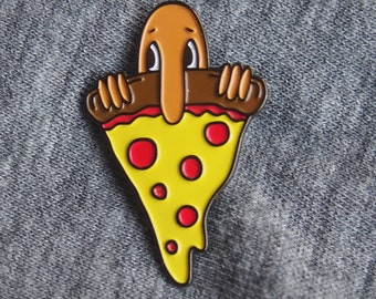 May include: A brown and yellow enamel pin of a cartoon character with a long nose peeking out from behind a slice of pizza with red pepperoni.