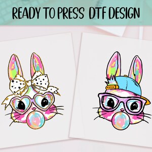 May include: Two DTF (Direct to Film) designs featuring cartoon bunnies. One bunny wears heart-shaped glasses and a bow, the other wears a cap and glasses. Both have bubblegum bubbles and colorful ears. The text "READY TO PRESS DTF DESIGN" is at the top.