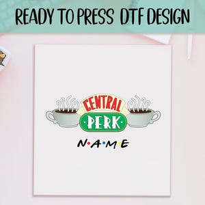 May include: White graphic featuring the Central Perk logo with two coffee cups and the text "CENTRAL PERK" in red and green. Below, the word "NAME" is written in a colorful font. The words "READY TO PRESS DTF DESIGN" are at the top.