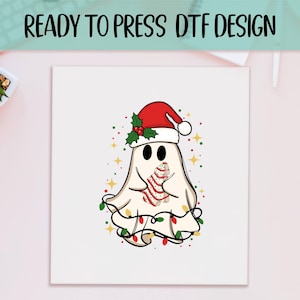 May include: A whimsical illustration of a ghost wearing a Santa hat and holding a Christmas tree cookie. The ghost is adorned with a string of colorful Christmas lights and surrounded by star-shaped accents. The text "READY TO PRESS DTF DESIGN" is at the top.