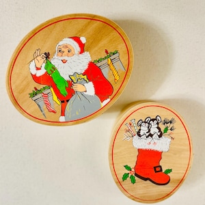 Könnte beinhalten: Zwei Weihnachtsdekorationen aus Holz. Ein ovales Ornament zeigt den Weihnachtsmann in rotem Anzug, der einen grünen Strumpf und einen grauen Sack hält. Das andere runde Ornament zeigt einen roten Stiefel mit Schnalle und zwei Mäusen.