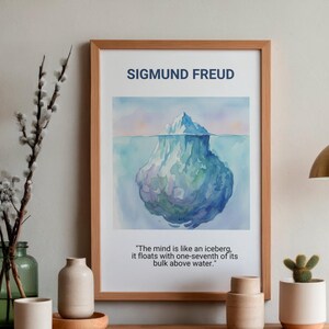 May include: A framed print featuring a watercolor painting of an iceberg. The print includes the name "SIGMUND FREUD" at the top and a quote about the mind. The frame is a light brown color, and the artwork has blue and green hues.