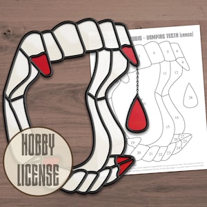 May include: A stained glass pattern of a vampire's hand with fangs and a red blood drop. The pattern is numbered for a stained glass project. The image also includes the text "HOBBY LICENSE" and "STUDIO - VAMPIRE TEETH (LARGE)".