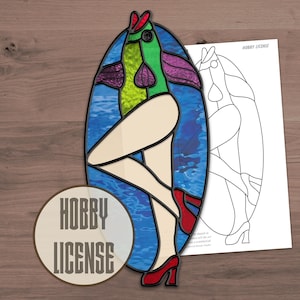 May include: A stained glass artwork featuring a woman with a fish head, wearing a swimsuit. The woman is standing in a blue oval with a wavy pattern. The artwork is labelled "Hobby License".