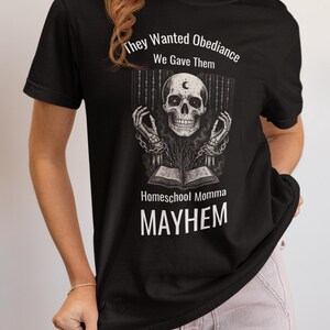 May include: Black t-shirt with a graphic design featuring a skull with a crescent moon, chains, and an open book. The text reads "They Wanted Obedience, We Gave Them" and "Homeschool Momma MAYHEM."