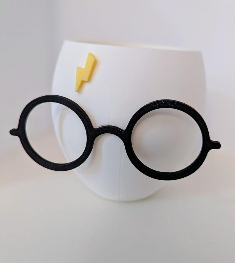 May include: White ceramic mug with a black lightning bolt decal and a pair of black round glasses attached to the side.
