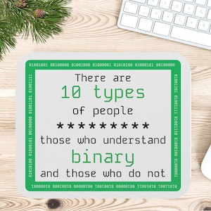 May include: A white mousepad with the text "There are 10 types of people: those who understand binary and those who do not" in green. A white mouse and keyboard are in the background.
