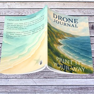 May include: An open Drone Journal with a coastal landscape illustration. The cover reads "DRONE JOURNAL" and "PRINT IT YOUR WAY." The journal's pages feature text about capturing sky-bound moments and drone flight tracking.