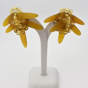 Pendientes de clip vintage firmados por Renoma Paris con cuentas y barras de lucita amarilla. Joyas retro con un diseño único y audaz.