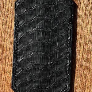 May include: A black leather patch with a snakeskin pattern and a stitched edge.