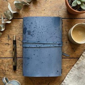 May include: A white ceramic mug with a black handle and the text "But First, Coffee" in a black, bold font. The mug is sitting on a wooden surface. The mug is 4 inches tall.