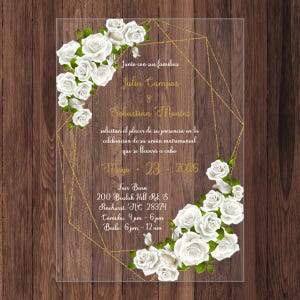 May include: A wedding invitation with a gold geometric frame and white roses. The invitation reads "Junto con sus familias Julia Campos y Sebastian Montes solicitan el placer de su presencia en la celebración de su unión matrimonial que se llevará a cabo Mayo 23, 2016 Fair Barn 200 Beulah Hill Rd. S Pinehurst, NC 28374 Comida, 4pm-6pm Baile, 6pm-12am"