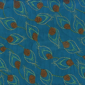 May include: Teal fabric with an embroidered peacock feather pattern. The feathers are brown with yellow and green stitching details. The design is repeated across the fabric, creating a textured and decorative surface.
