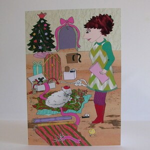 May include: A woman in a green and yellow dress stands in a room with a Christmas tree, presents, and a white cat. She is holding a pink piece of paper. The room is decorated with a pink bow and a purple door.