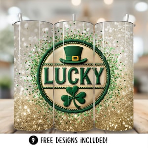 May include: A set of three stainless steel tumblers with a St. Patrick's Day theme. The design features a green hat, a shamrock, and the word "LUCKY" on a cream-colored background, surrounded by green glitter and gold sparkles. The bottom of the tumblers have gold glitter.