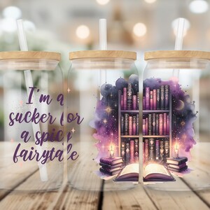 May include: Three glass jars with bamboo lids and straws. The jars have a watercolor design of a bookshelf with books and a glowing book in front of it. The text on the jar reads "I'm a sucker for a spice fairy tale".