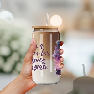 May include: A clear glass tumbler with a gold lid and a straw. The tumbler has a purple and pink watercolor design with stars and the text "Once a reader for a spicy fairytale".