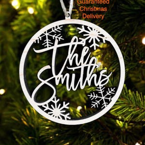 a Christmas ornament with the name "The Smiths" written on it, hanging on a tree.