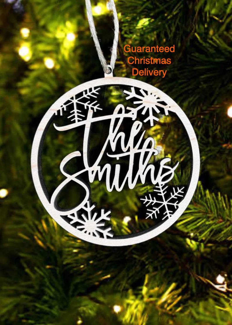 a Christmas ornament with the name "The Smiths" written on it, hanging on a tree.
