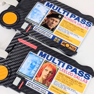 Puede incluir: Dos tarjetas de identificación Multi Pass rectangulares de plástico con textura de fibra de carbono negra, un botón naranja circular y enganches blancos. Cada tarjeta muestra un retrato, datos personales y el texto Multi Pass Korben o Leeloo Dallas.