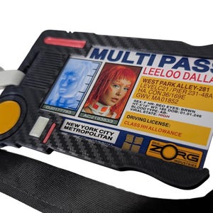 Peut inclure: Un porte-badge en plastique noir à texture fibre de carbone affichant un Multi Pass pour Leeloo Dallas. La carte présente une photo d'une personne aux cheveux orange, des données personnelles, un bouton circulaire jaune et le logo Zorg Industries.