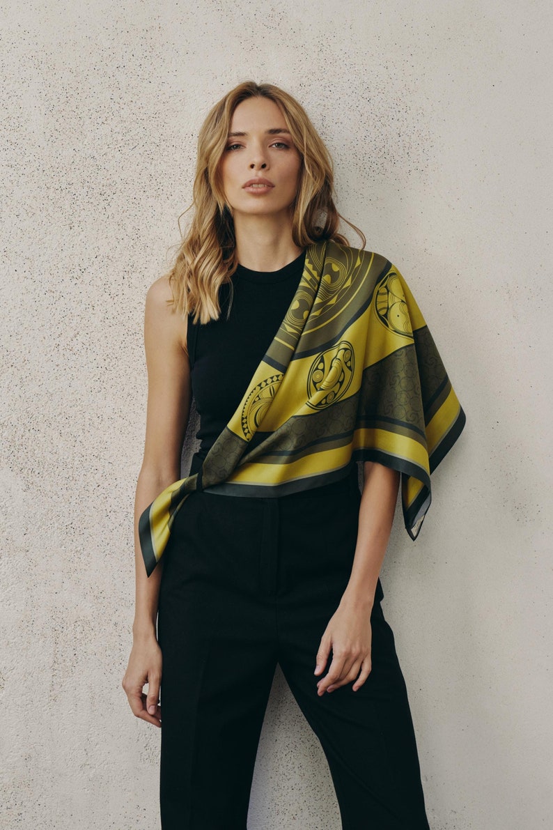May include: A woman wearing a black tank top and black pants with a yellow and green patterned scarf draped over her shoulder.