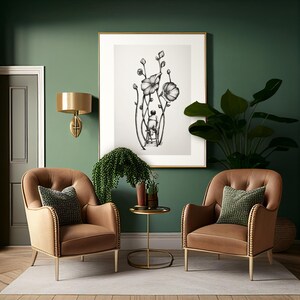 May include: Two brown leather armchairs with tufted backs and gold legs, facing each other in a room with green walls. A black and white drawing of a person standing in a field of flowers hangs on the wall above a small gold side table.