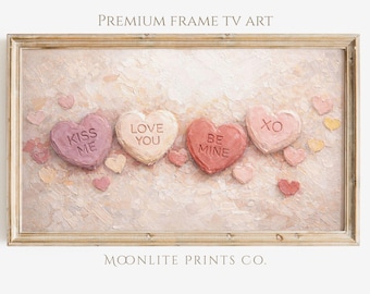 May include: A framed digital art print featuring four heart-shaped candies with romantic phrases: "Kiss Me," "Love You," "Be Mine," and "XO." The artwork has a textured, painterly style with a soft, pastel color palette of pinks and creams. The frame is a light wood color.