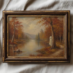 May include: A framed landscape painting featuring a calm lake surrounded by autumn trees with orange and brown foliage. A white ghost figure stands partially hidden behind a large tree trunk on the right side of the path near the water's edge.