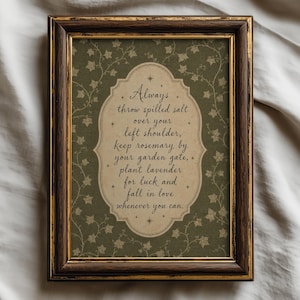 May include: A framed wall art print featuring a dark olive green background with a white ivy vine pattern. Centered is a beige scalloped label containing the text: Always throw spilled salt over your left shoulder, keep rosemary by your garden gate, plant lavender for luck and fall in love whenever you can. The frame is dark brown wood with gold trim.