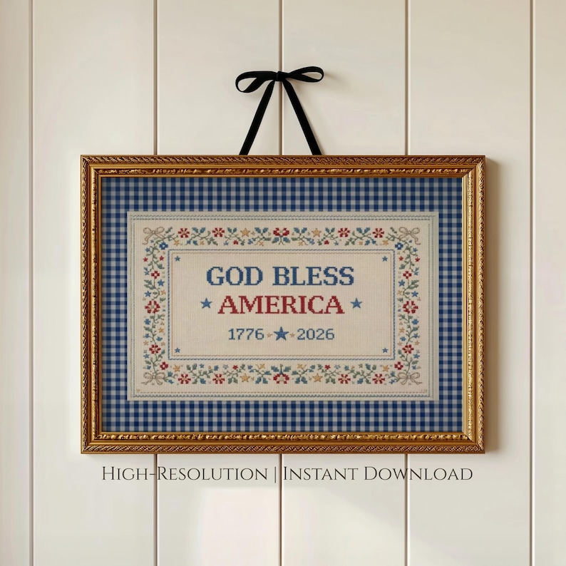 May include: Framed wall art with a gold-colored frame and a black ribbon for hanging. The artwork features a blue and white gingham background with a central embroidered design that reads "GOD BLESS AMERICA" and the years "1776 - 2026".