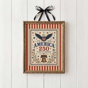 Puede incluir: Obra de arte patri&oacute;tica enmarcada con una combinaci&oacute;n de colores rojo, blanco y azul. El dise&ntilde;o presenta un &aacute;guila, estrellas y el texto "AMERICA 250 YEARS OF FREEDOM" dentro de un borde decorativo. Una cinta negra est&aacute; adjunta para colgar.