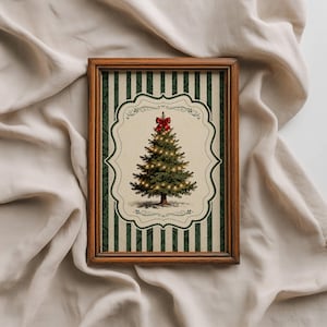 May include: A rectangular wooden frame containing a print of a green Christmas tree with glowing lights and a red bow on top. The print features a cream-colored central scalloped label set against a background of dark green and cream vertical stripes.