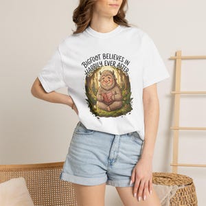 Bigfoot Believes in Happily Ever After Cryptid T-shirt | Sasquatch Reading in Forest