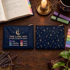 May include: Two rectangular navy blue zippered pouches. The left pouch features a gold crescent moon and sword graphic with the text THE LORE KEY for readers of magic and mayhem, plus a color-coded legend. The right pouch has a gold celestial pattern.