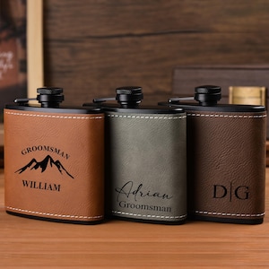 Puede incluir: Tres petacas personalizadas en polipiel marrón, verde oliva y marrón oscuro. La petaca marrón tiene "Groomsman" y "William" con un gráfico de montaña. La petaca verde oliva tiene "Adrian Groomsman". La petaca marrón oscuro tiene "DG".
