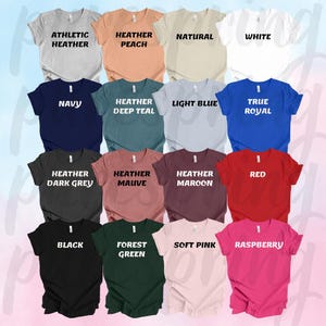 May include: A collection of 16 t-shirts in various colors, including athletic heather, heather peach, natural, white, navy, heather deep teal, light blue, true royal, heather dark grey, heather mauve, heather maroon, red, black, forest green, soft pink, and raspberry. Each shirt has a different color and text label.