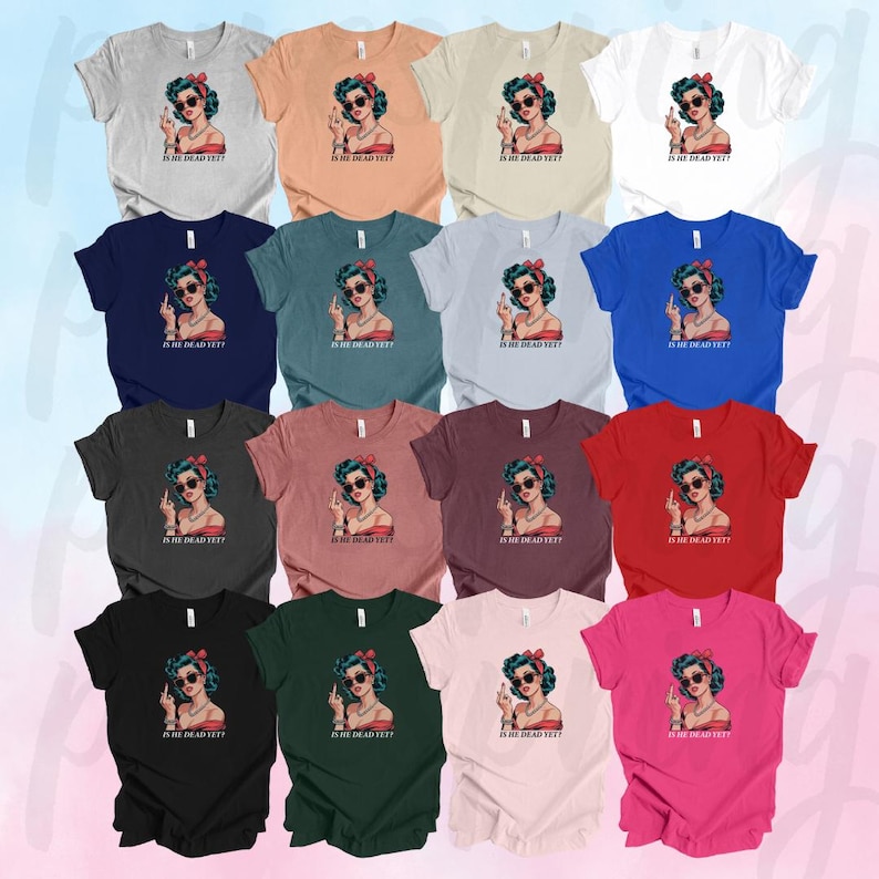 May include: A collection of 12 t-shirts in various colors featuring a retro-style illustration of a woman with blue hair and red lipstick. The woman is giving a middle finger and the text "Is he dead yet?" is printed on the shirt.