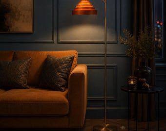 May include: A floor lamp with a thin, gold-toned metal stand and a circular base. The lamp features a tiered, stepped shade made of concentric wooden rings in a warm, reddish-brown finish that emits a soft, downward-facing light.