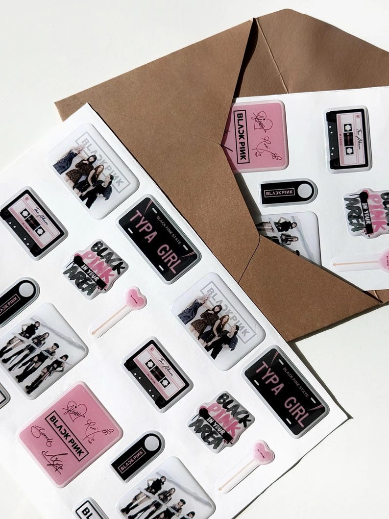 May include: A collection of stickers featuring the text "BLACKPINK" and images of a music cassette, a license plate that says "TYPA GIRL", and a group of people. The stickers are in pink, black, and white.